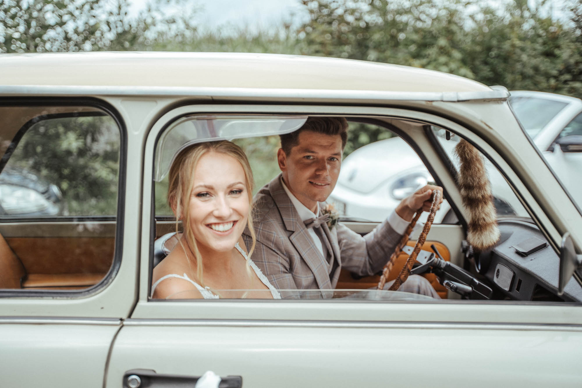 Brautpaar im Brautauto - nach der Trauung auf dem Weg zur Hochzeitslocation